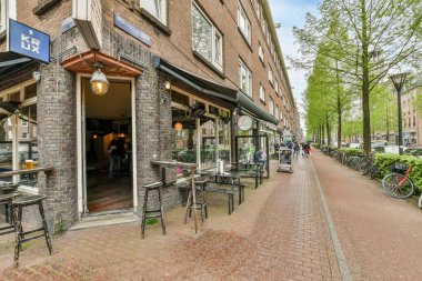 Bisikletleri kaldırımda park etmiş bir restoranın önünde ve önünde yürüyen insanlar.