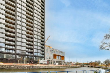 Amsterdam, Hollanda - 10 Nisan 2021: Önünde binalar ve su bulunan bir kentsel alan - nehir kıyısındaki bir tekneden alındı