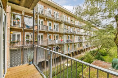 Amsterdam, Hollanda - 10 Nisan 2021: Balkonları ve balkonları olan bir apartman kompleksi, ikinci kattaki ağaçlar - Swayr