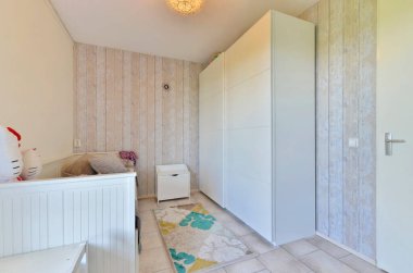 Beyaz duvarları ve duvarlarında tahta duvar kağıtları olan bir oda. Köşesinde de büyük bir ayna var.