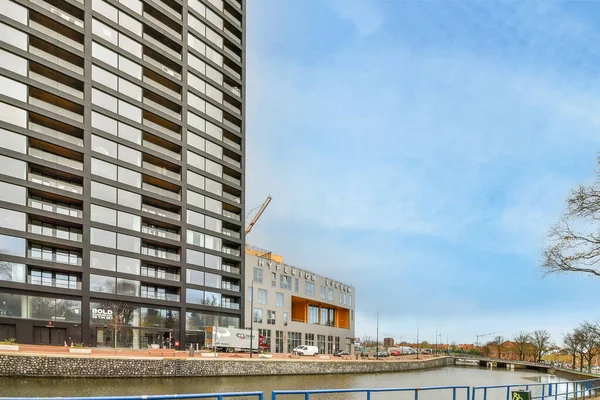 Amsterdam, Hollanda - 10 Nisan 2021: Önünde binalar ve su bulunan bir kentsel alan - nehir kıyısındaki bir tekneden alındı