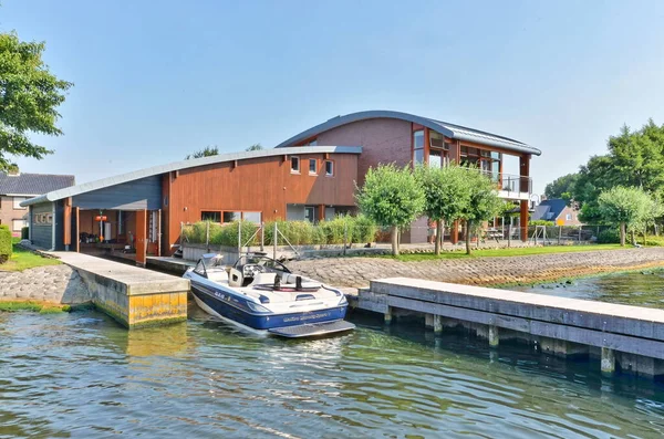 stock image a house on the water with a boat tied to its dock and two houses in the back ground