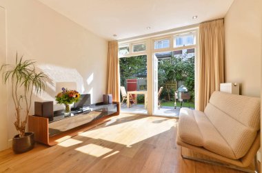 Ahşap döşemeli ve verandaya açılan cam kapaklı bir oturma odası.