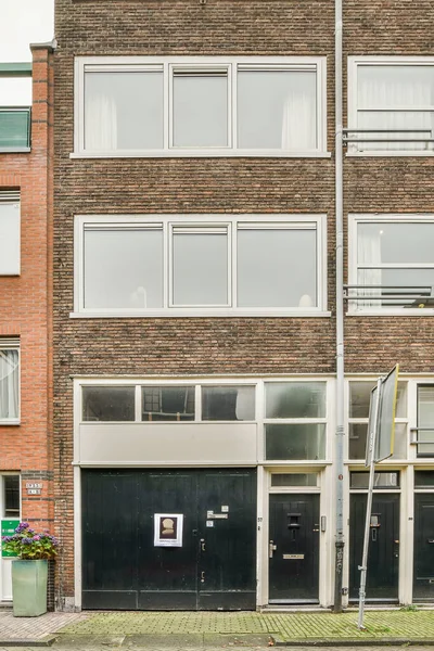 stock image Amsterdam, Netherlands - 10 April, 2021: a brick building with two garages in the front and one on the other side there is an empty street