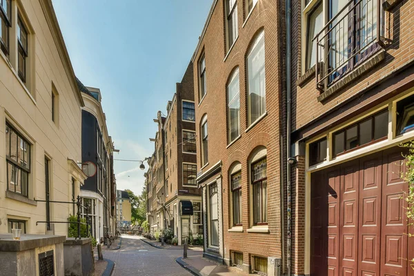 荷兰阿姆斯特丹 2021年4月10日 市区一条狭窄的街道 两边都有砖楼 红门通往右边 — 图库照片