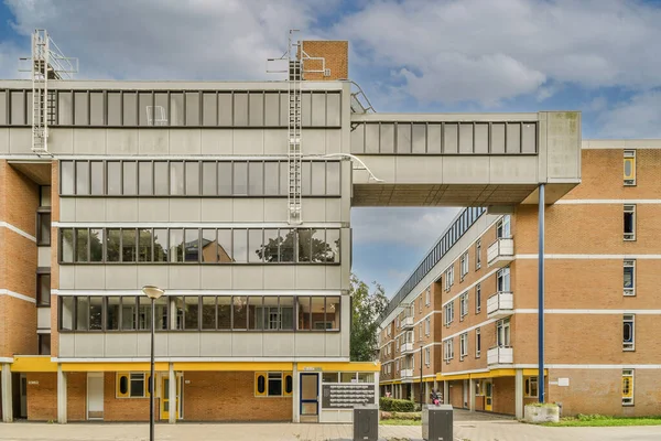 stock image Amsterdam, Netherlands - 10 April, 2021: a building that is in the middle of an urban area with some people walking on the sidewalk and cars parked nearby