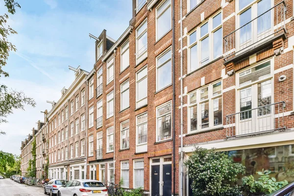 stock image Amsterdam, Netherlands - 10 April, 2021: a city street with cars parked on the curbs and buildings in the background, taken from the car window