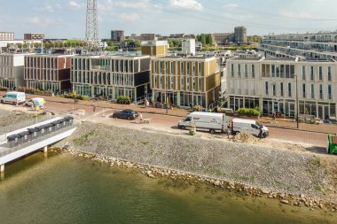 Amsterdam, Hollanda - 10 Nisan 2021: köprü önünde nehir kenarına park edilmiş bina ve araçların bulunduğu bir şehir alanı