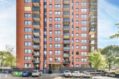 Amsterdam, Hollanda - 10 Nisan 2021: Arabaların park edildiği bir apartman ve insanların park alanında yürüdüğü bir apartman.