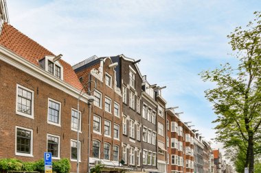 Yan tarafında arabalar ve arka tarafında binalar olan bir caddede bazı insanlar sokakta yürüyorlar.