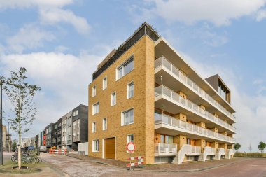 Amsterdam, Hollanda - 10 Nisan 2021: Önünde arabalar park edilmiş bir apartman dairesi ve dışarıda yürüyen insanlar