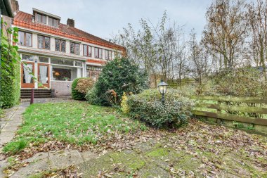 Amsterdam, Hollanda - 10 Nisan 2021: Yere düşen bir ev ve önünde yaprakları olmayan bir ağaç var.