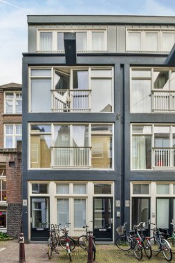 Amsterdam, Hollanda - 10 Nisan 2021: Bir apartmanın önüne park edilmiş iki bisiklet ve ikinci kattaki camlara yapışmış engeller.