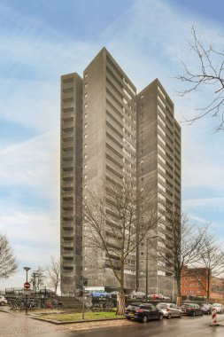 Amsterdam, Hollanda - 10 Nisan 2021: Arkasında arabalar olan bir apartman ve arka planda bazı binalar çıplak ağaçlardır.