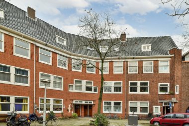 Amsterdam, Hollanda - 10 Nisan 2021: Önünde iki bisiklet olan kırmızı tuğladan bir apartman ve evin yanındaki caddede bir bisiklet.