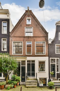 Amsterdam 'ın ortasında eski bir ev, önünde saksı bitkileri, arkasında da iki katlı evler.
