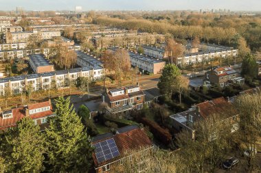 Amsterdam, Hollanda - 10 Nisan 2021: Evleri ve ağaçları olan bir şehir - bazı binalara bakan havadan çekilmiş bir fotoğraf