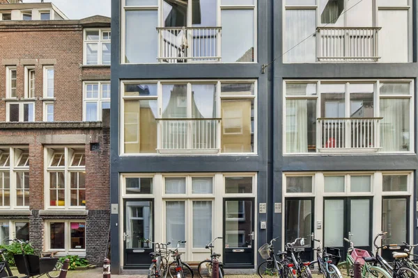 2021年4月10日 荷兰阿姆斯特丹 一些自行车停放在街道两侧的建筑物前 有许多窗户和包包在后面 — 图库照片