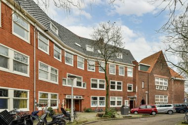 Amsterdam, Hollanda - 10 Nisan 2021: Bazı motosikletler tuğlalı bir binanın önüne park edilmiş ve üst ve alt katlarında birçok pencere var.