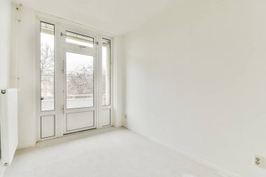 Köşesinde kapısı ve penceresi olan boş bir oda. Temiz görünmesi için beyaza boyanmış.