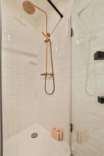 シャワースタンドにはシャワーヘッドと手があるバスルーム壁には白いタイル — ストック写真