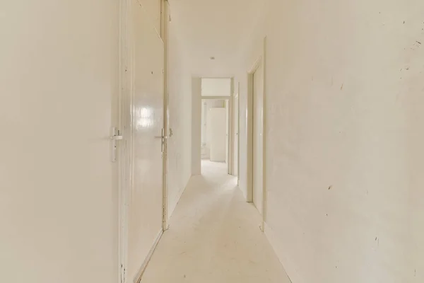 右側の壁に白い壁と木のトリムの長い廊下は別の部屋につながるオープンドアです — ストック写真