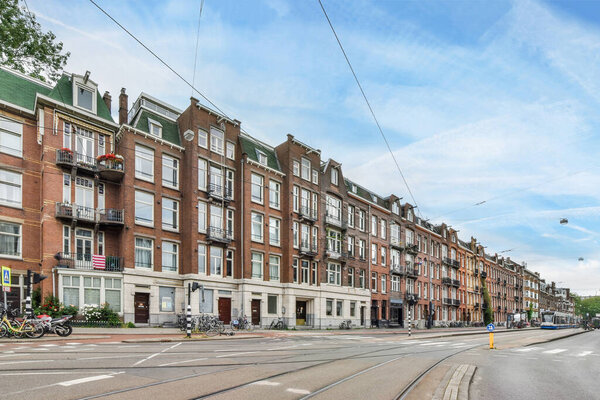Amsterdam, Netherlands - 10 April, 2021: a city street with buildings on both sides and cars driving down the street in front of them all along the road