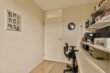 Amsterdam, Hollanda - 10 Nisan 2021: Sandalyesi ve kitapçığı olan küçük bir odadaki masanın yanındaki duvarda yaşlı bir adam