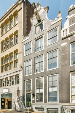 Amsterdam, Netherlands - 10 April, 2021: an apartment building with many windows and bales on the top floor, as seen from the street in front