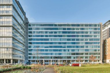 Amsterdam, Hollanda - 10 Nisan 2021: Binanın her iki tarafında da birçok pencere ve fabrika bulunan bir ofis binası açık mavi gökyüzü