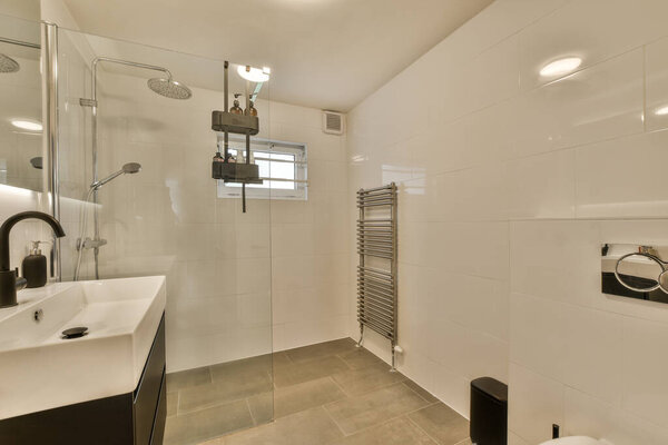 a modern bathroom with white tiles and black fixtures on the walls, along with a toilet in the corner to the shower stall is