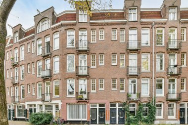 Amsterdam, Hollanda - 10 Nisan 2021: Önünde birçok pencere ve engeller olan bir apartman dairesi, pencere kutularında bazı bitkiler büyüyor