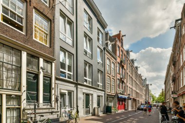 Her apartmanın önünde yol kenarına park edilmiş binaları ve bisikletleri olan bir şehir caddesi.,