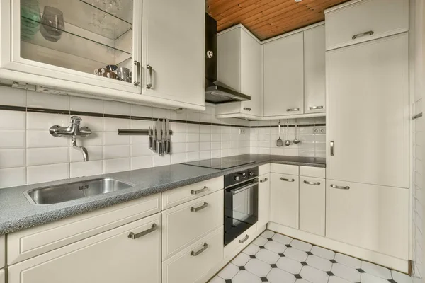 在这张照片的柜台上有白色的橱柜和黑色的台面的厨房是从里面拍摄的 — 图库照片