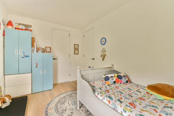 детская комната с кроватью, шкафами и другими вещами на стене окрашена в белый цвет