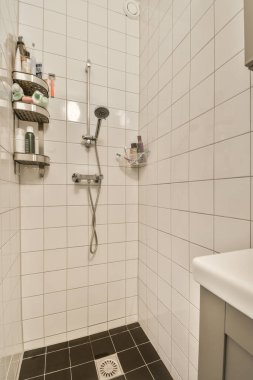 Duvarlarında siyah beyaz fayanslar, duş başlıkları ve köşede tuvalet olan bir banyo.