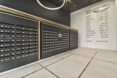 Amsterdam, Hollanda - 10 Nisan 2021: Duvarda beyaz harflerle etiketlenmiş bir sürü kutu ve çöp kutusu olan büyük bir odanın içi