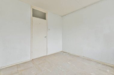 Beyaz duvarları olan boş bir oda ve diğer duvarda hiç kapı yok. Köşede küçük bir pencere var.
