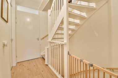 Altında ahşap korkuluklar olan beyaz bir merdiven ve bir apartmanın ikinci katına çıkan merdivenler.