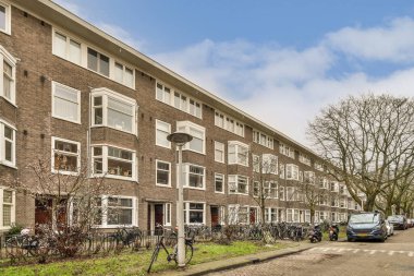 Kaldırımda bisikletleri olan bir apartman ve caddenin arkasına park etmiş arabalar, hepsi sıraya dizilmiş.