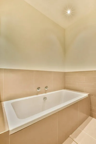 房间角落里的浴缸 墙上挂着米黄色的瓷砖 旁边坐着一个白色的浴缸 — 图库照片