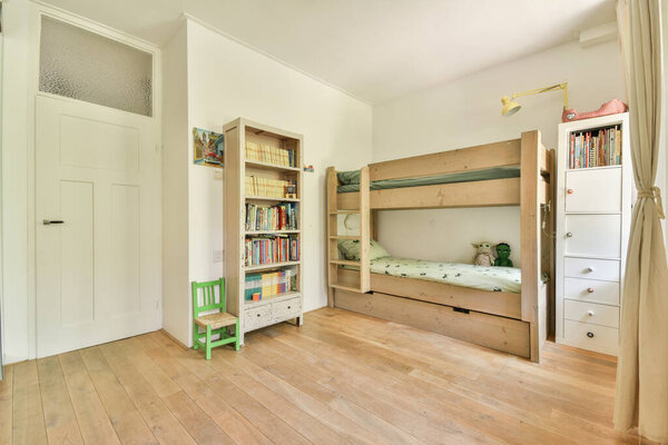 детская комната с кроватями, книжным шкафом и другими вещами на полу перед кроватью