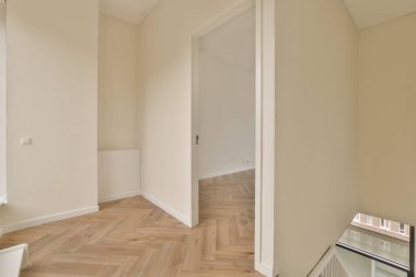 Fotoğrafta tahta döşemeli ve beyaz duvarlı boş bir oda sağdaki kapıdan çekiliyor.