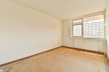 Beyaz duvarları ve ahşap döşemeleri olan boş bir oda. Duvarda bir pencere var.