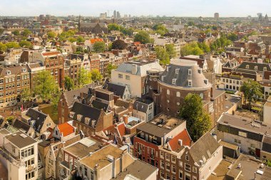 Amsterdam, Hollanda - 10 Nisan 2021: Bir binanın tepesinden bir şehir. Görüntünün ortasında bir sürü bina ve diğer tarafında ağaçlar var.