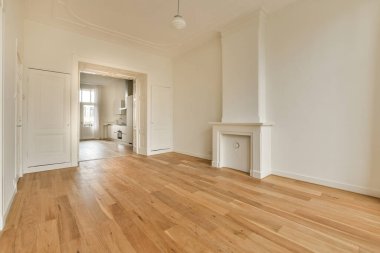 Bu fotoğrafta duvarlarında ahşap döşeme ve beyaz süsleme olan boş bir oturma odası ön kapıdan çekilmiştir.