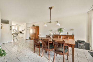 Odanın ortasında fayans döşemeleri ve ahşap mobilyaları olan bir yemek odası açık bir mutfak alanıdır.