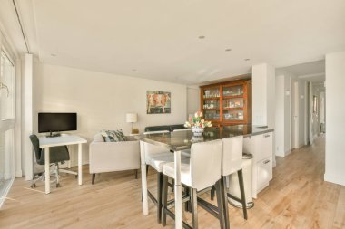 Ahşap zemin, beyaz duvarlar, ahşap döşemeler ve geniş pencereli bir dairede mutfak ve oturma odası.