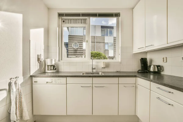 Eine Küche Mit Weißen Schränken Und Schwarzen Arbeitsplatten Auf Den — Stockfoto