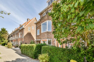 Amsterdam, Hollanda - 10 Nisan 2021: Her iki tarafında yeşil bitkiler ve çalılar olan bir bölgenin ortasında parlak mavi bir gökyüzü var.